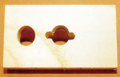 wood board with two holes with the center one having two notches carved out on either side